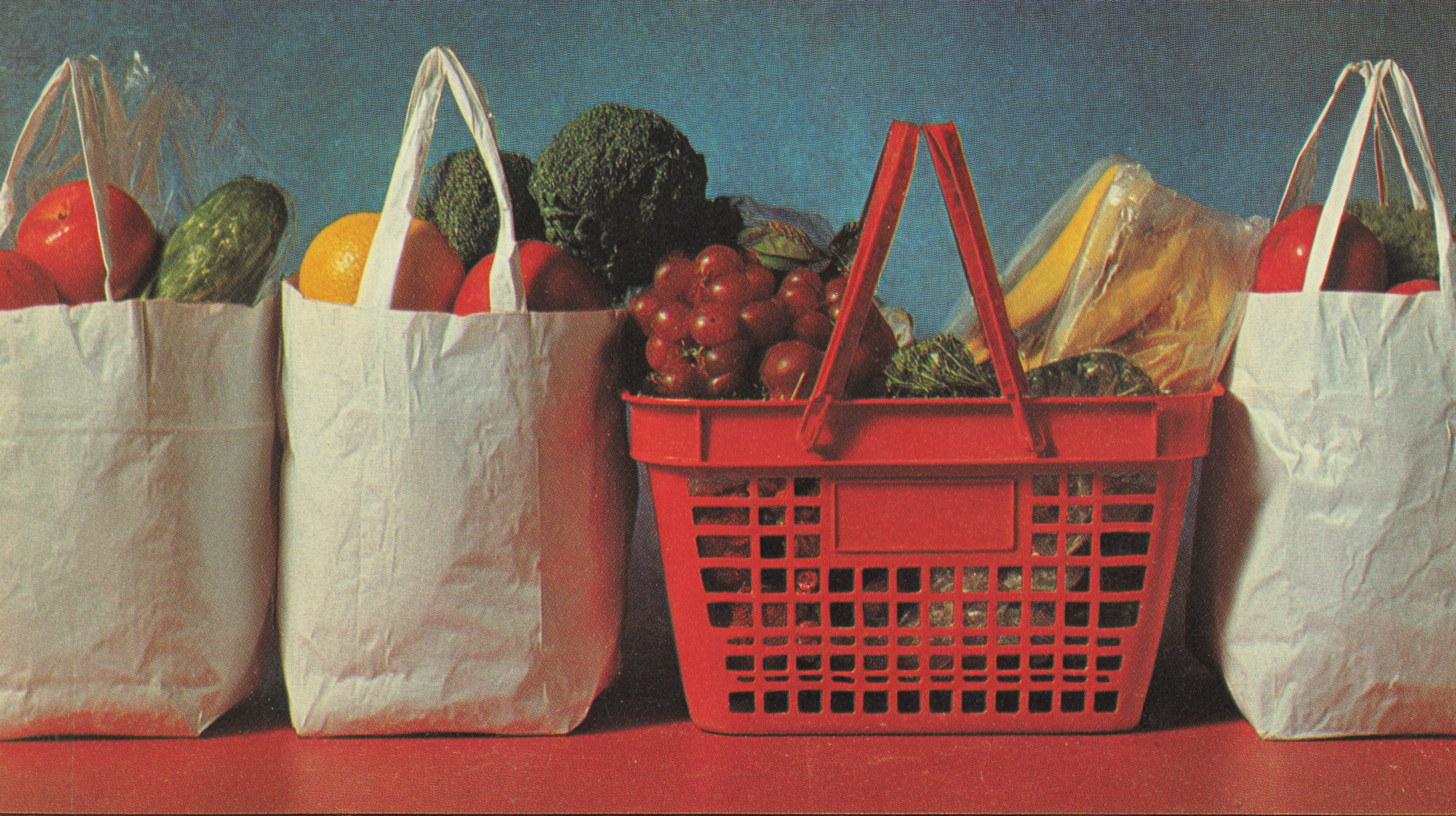 Row of white grocery bags and a red shopping basket filled with produce